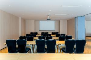 une salle de conférence avec des tables, des chaises et un écran dans l'établissement Holiday Inn Express Hangzhou Airport, an IHG Hotel, à Hangzhou