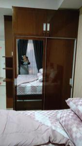 een persoon die een foto neemt van een bed in een spiegel bij Apartemen Skylounge Makassar in Manda