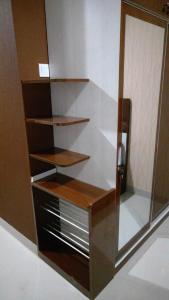a closet with wooden shelves and a glass door at Apartemen Skylounge Makassar in Manda