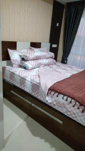 a bedroom with two beds with pink and white sheets at Apartemen Skylounge Makassar in Manda