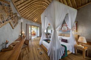a bedroom with a bed with white mosquito nets at thewakanda Resort A Pramana Experience in Ubud