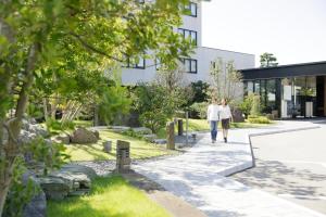two people walking down a sidewalk in front of a building at Kanazawa Sainoniwa Hotel in Kanazawa