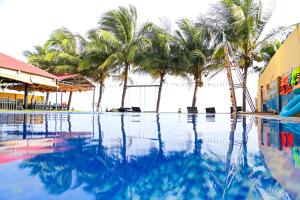 a swimming pool with palm trees in the background at Venus MuiNe in Mui Ne