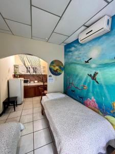 Zimmer mit einem Bett und einem Wandgemälde in der Unterkunft Nelyza's Suites & Adventure in Puerto Ayora