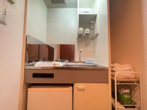 uma pequena cozinha com um lavatório e um espelho em マルチステイ大阪京橋32 em Osaka