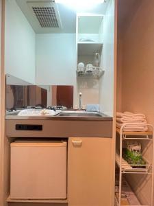 uma pequena cozinha com um lavatório e um fogão em マルチステイ大阪京橋32 em Osaka
