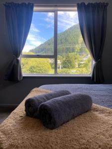 a bed with a large window with a view of a mountain at Alpine Lodge Queenstown in Queenstown