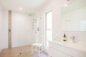 a white bathroom with a sink and a chair at The Treehouse Vincentia in Vincentia +32 photos