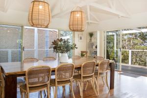 a dining room with a wooden table and chairs at The Treehouse Vincentia in Vincentia