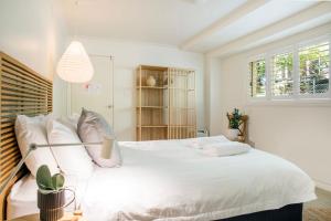 a bedroom with a large white bed with white pillows at The Treehouse Vincentia in Vincentia