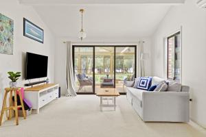 a living room with a couch and a tv at Waterfront Pet-Friendly Abode - Toukley NSW in Toukley