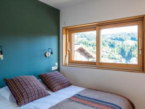 ein Bett mit zwei Kissen in einem Zimmer mit einem Fenster in der Unterkunft Chalet Les Gets, 5 pièces, 8 personnes - FR-1-671-245 in Les Gets