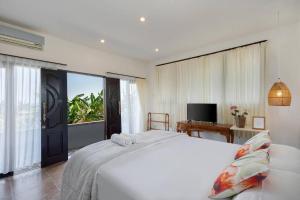 a bedroom with a white bed and a large window at Desiderata Villa - Villa Asri Karangasem in Karangasem