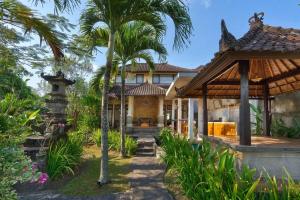 an exterior view of a house with palm trees at Desiderata Villa - Villa Asri Karangasem in Karangasem