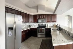 a kitchen with wooden cabinets and a stainless steel refrigerator at Havasu Retreat! Pool, Spa, Gym & View in Lake Havasu City