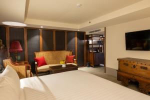 een slaapkamer met een bed, een stoel en een tafel bij Payaa Hotel in Pattaya