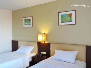 a hotel room with two beds with white pillows at Naris Art Hotel in Pattaya South