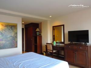 a bedroom with a bed and a desk with a flat screen tv at Naris Art Hotel in Pattaya South
