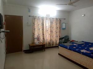 1 dormitorio con cama, mesa y cortina en Holiday Tourisms Group of Homestay Food Scuba Diving Boating Watersports-Tarkarli-Devbag Beach en Bhogwe