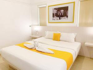 a bedroom with a bed with two white and yellow sheets at Victoria Bed & Breakfast in Malang