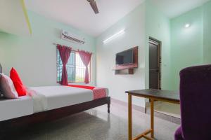 a bedroom with a bed and a table and a tv at OYO Flagship 81152 Hotel Raz Stays in Bhubaneshwar
