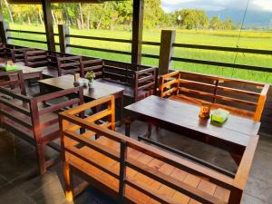 a restaurant with wooden tables and chairs and a field at PURI LESTARI in Sorongjukung