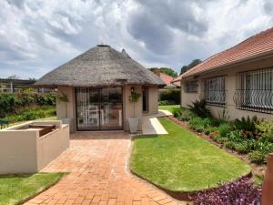 a house with a thatch roof and a patio at Isabel's B & B in Krugersdorp