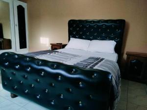 a bedroom with a bed with a black headboard at Faith and Grace Guest House in Lamin