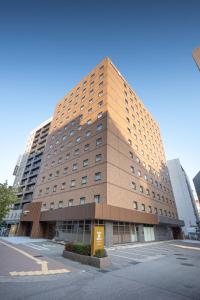 Un palazzo alto in una città con una strada di Smile Hotel Premium Kanazawa Higashiguchiekimae a Kanazawa
