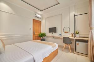 a bedroom with a bed and a desk and a television at Bin Bin 10 - Mimosa Hotel Near Tan Son Nhat Airport in Ho Chi Minh City