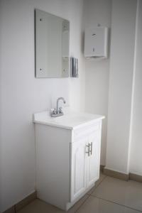 La salle de bains blanche est pourvue d'un lavabo et d'un miroir. dans l'établissement HOSPEDAJE Y MIRADOR EL ANGEL, à Calvillo