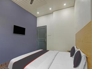 a bedroom with a bed and a tv on the wall at Collection O Hotel Shubharambh in Kānpur