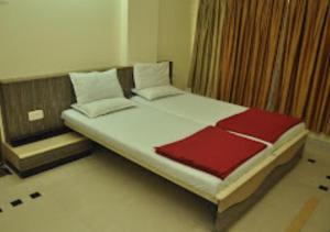 una camera con un letto e un piumone rosso e bianco di Hotel Premier - Hotel in Saket Society Bhusawal a Bhusāwal