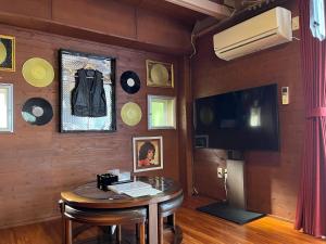 恩納村にあるヴィラフロムオキナワの木製の壁の客室で、テーブル、テレビが備わります。