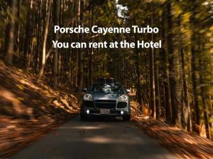 a car parked on a road in a forest at Hotel Montblanc Hakuba in Hakuba