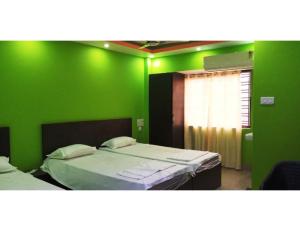 Hotel Invite, Agartala في آغارتالا: غرفة خضراء بسريرين ونافذة