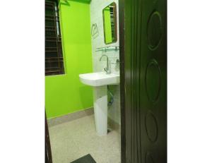 a bathroom with a sink and a green wall at Hotel Invite, Agartala in Agartala