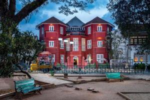 um grande edifício vermelho com bancos à sua frente em Koder House em Cochin