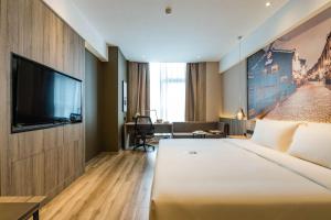 a hotel room with a large bed and a flat screen tv at Atour Hotel Ningbo Laowaitan in Ningbo