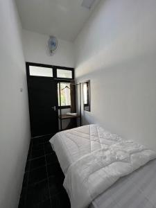 a bedroom with a white bed and a black door at White House Malioboro in Jetis
