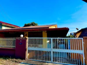 ein Haus mit einem weißen Tor davor in der Unterkunft Ramizu Homestay Pokok Sena in Pokok Sena