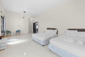 a white room with two beds and a table and chairs at Terminal Majesty Villa Haven 3bedroom near DXB T3 in Dubai
