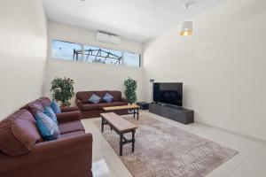 a living room with two couches and a tv at Terminal Majesty Villa Haven 3bedroom near DXB T3 in Dubai