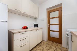 uma cozinha com armários brancos e um prato de fruta em Apartment Ivano em Vrbnik