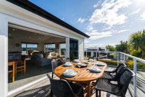 un tavolo e sedie in legno su una terrazza con una casa di Scenic Lake Views - Taupo Holiday Home a Taupo