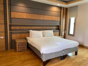 um quarto com uma cama grande e uma cabeceira. em Paragon Inn em Lat Krabang