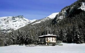 um edifício no meio de uma montanha coberta de neve em Hotel Le Campagnol em Champoluc