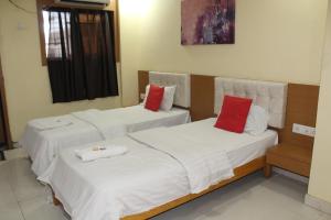 two beds in a room with white and red pillows at HOTEL SHIVRAI in Pen