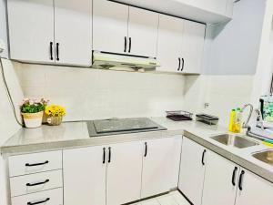 a white kitchen with white cabinets and a sink at 9 pax Homestay near Axiata Arena & Pavilion 2 in Kuala Lumpur