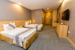 a hotel room with two beds and a flat screen tv at Madison 101 Hotel + Tower in Manila